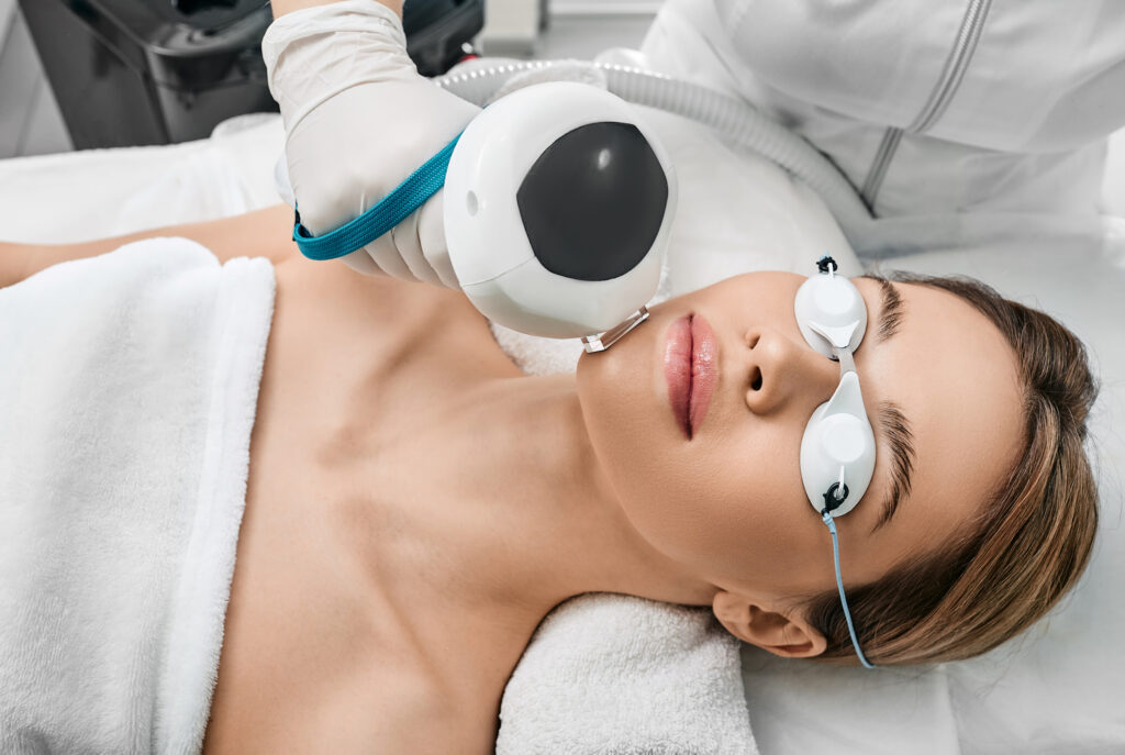 Photorejuvenation of a woman's face using intense pulsed light IPL with a beautician in a cosmetology salon for rosacea treatment, removing brown spots and vascular mesh