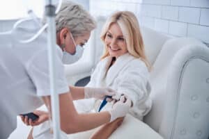 Older woman smiling while receiving IV Therapy for energy and skin hydration.